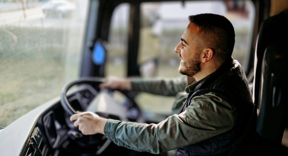 Smiling HGV driver at the wheel, demonstrating a driver-facing fleet CCTV system for behaviour monitoring