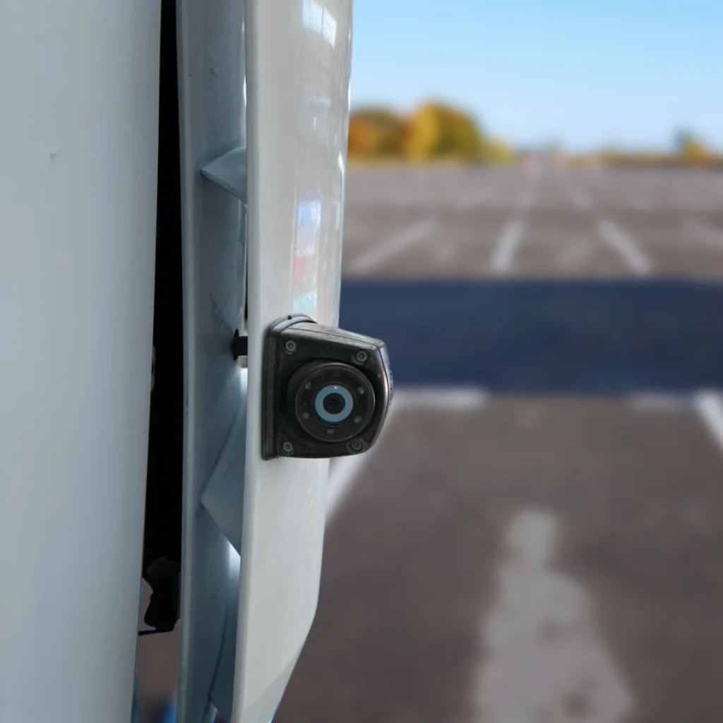 Close-up of a side-mounted blind spot camera on a white commercial vehicle