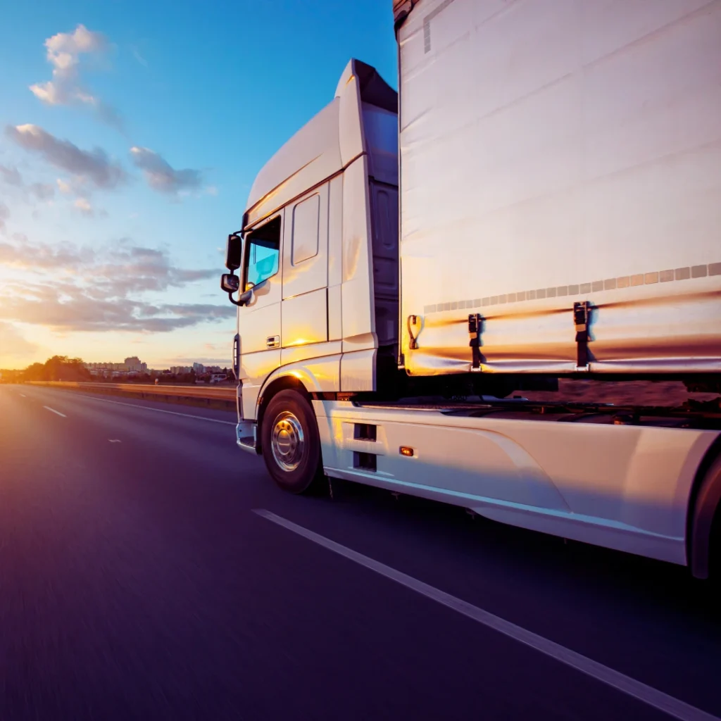 Articulated lorry driving along a motorway at sunset, side view