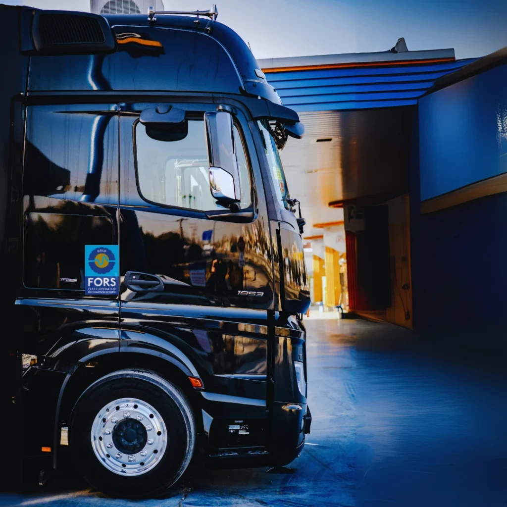 Side view of a black HGV displaying a FORS Gold accreditation sticker on the driver’s door