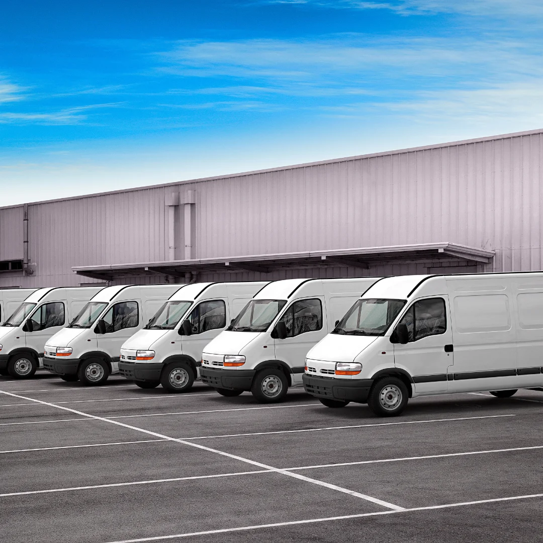 Row of white vans parked outside a distribution hub, representing fleet management and tracking