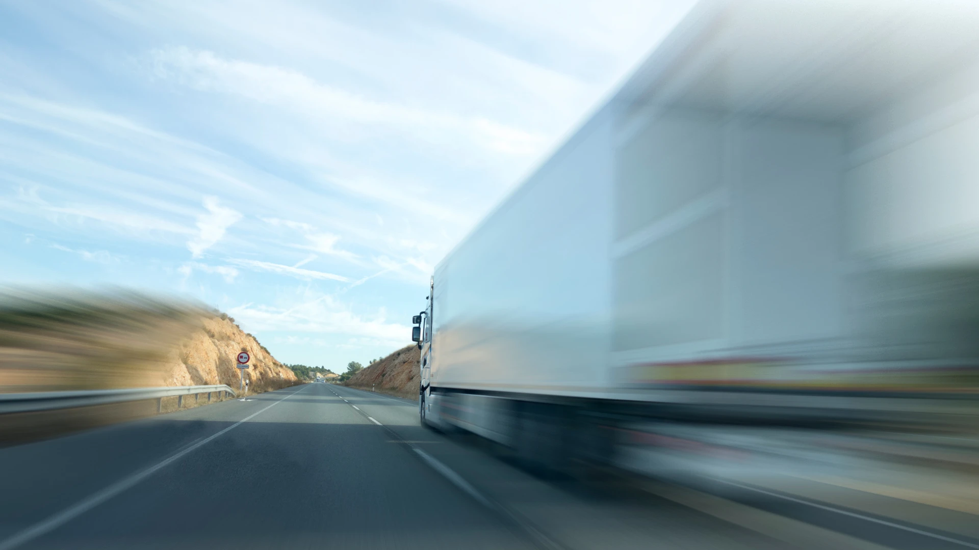 Large white HGV moving fast on a clear road with motion blur effect