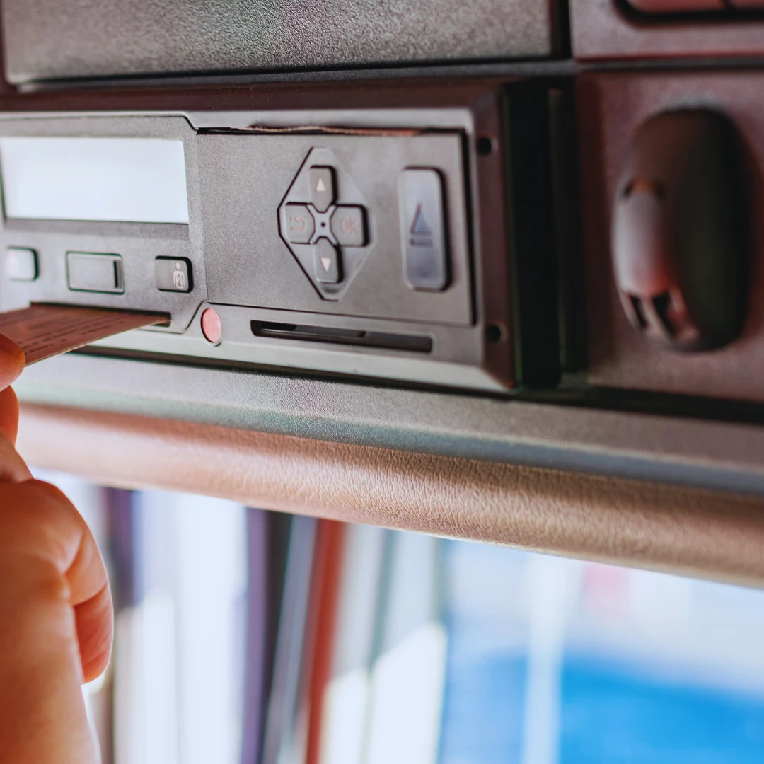 Driver inserting tachograph card into digital tachograph unit